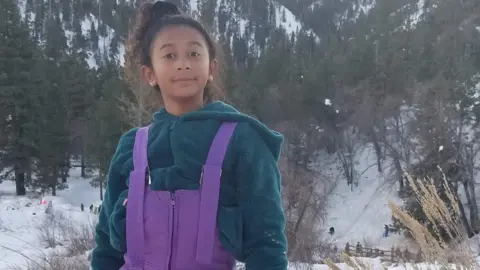 Courtesy of Celeste Rivas Hernandez's family Celeste Rivas Hernandez is seen in a snow outfit. She is wearing a teal jacket and bright purple overalls 